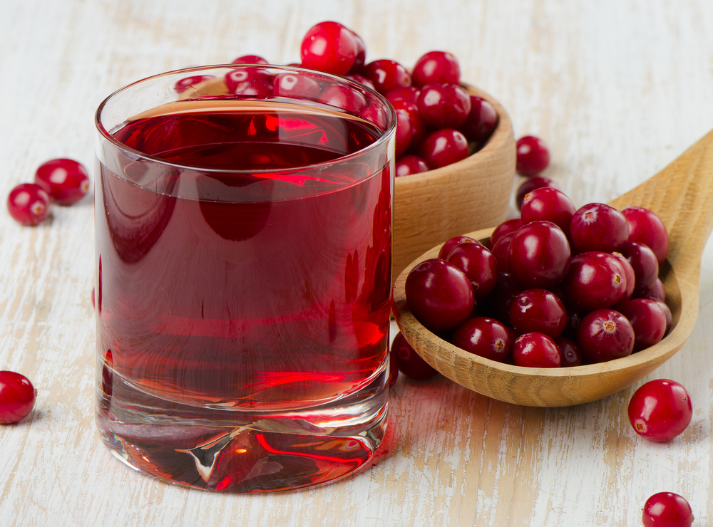 Cranberries in a  wooden spoon and glass of juice. Selective focus