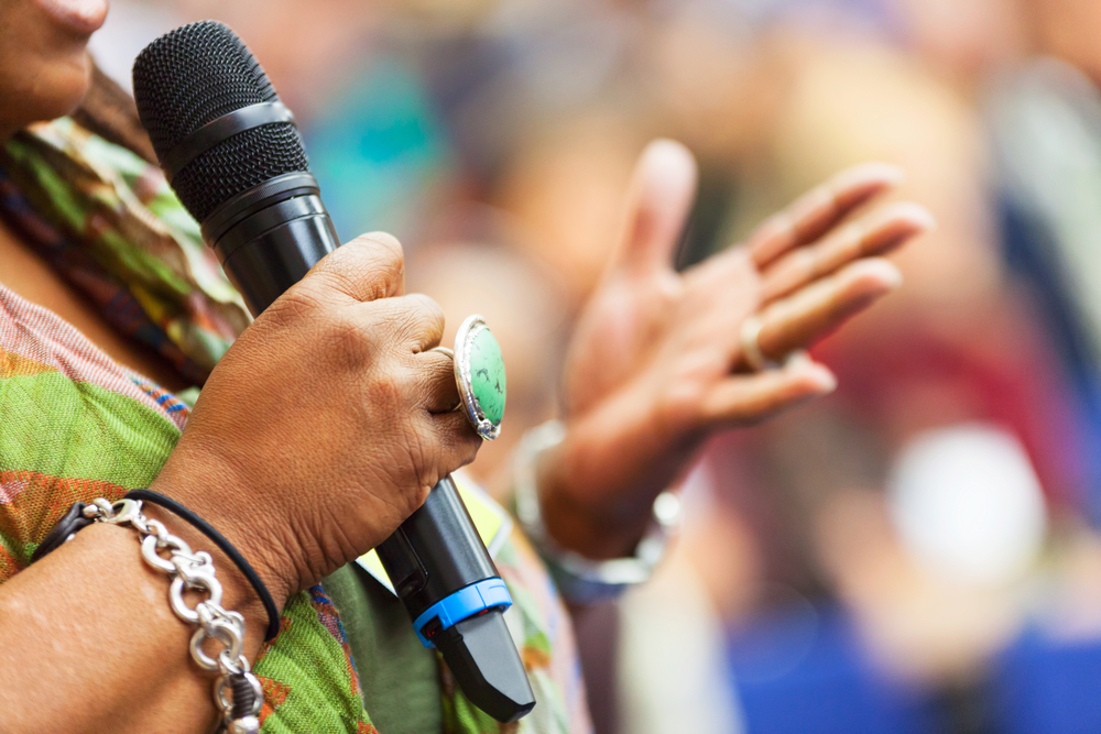 Women Speaking in to the microphone at the conference. Detail
