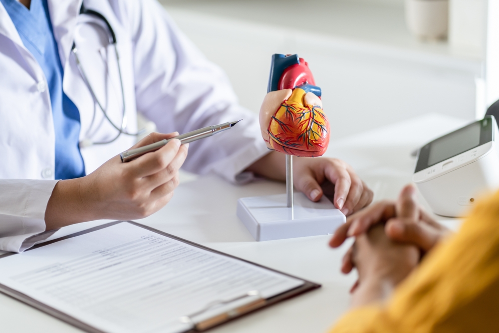 doctor with patient pointing to model of heart