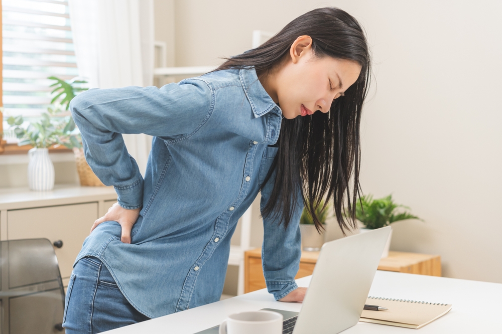 Body muscles hurt stiff, suffering asian young woman, girl back pain, body ache while stand up from desk at work, holding massaging rubbing back, problem health care of office syndrome people concept.