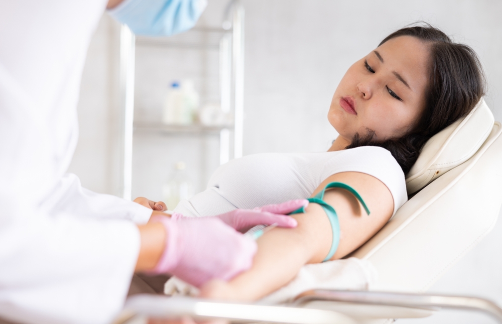 Skilled middle-aged doctor in uniform giving patient injection into vein