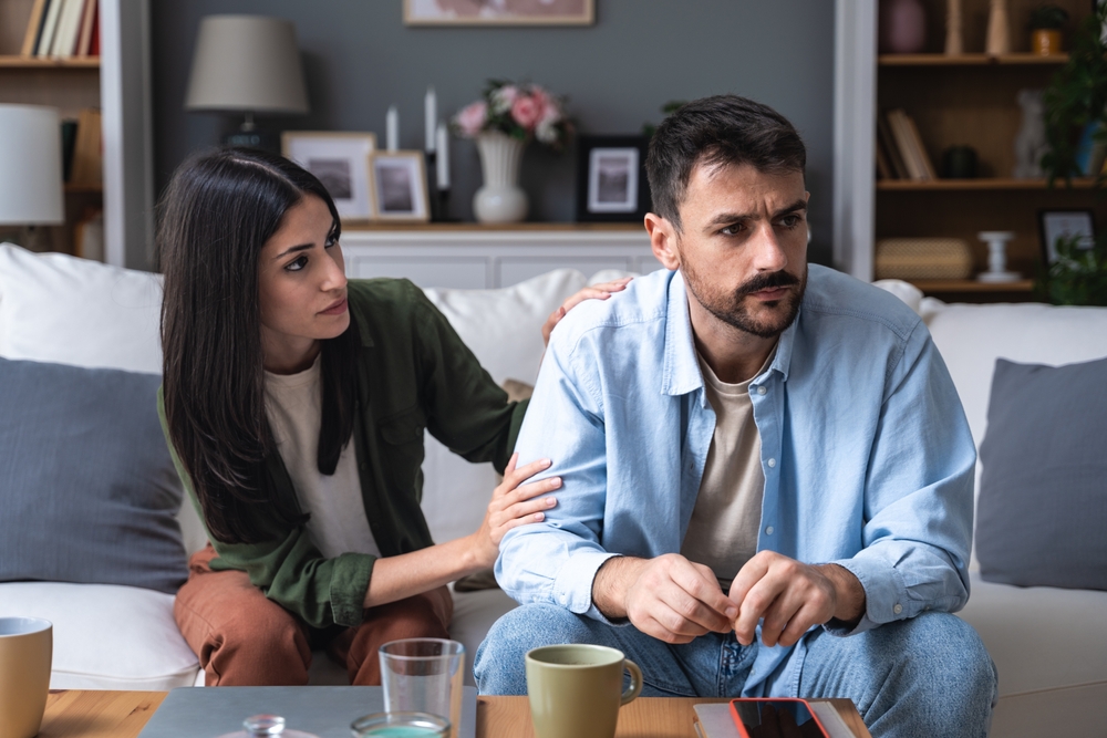 Young married couple husband and wife sitting at home having problems in their marriage and a cold relationship. A boyfriend and a girlfriend roommates have an argument about spending too much money
