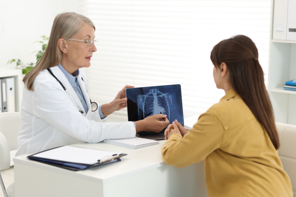 Lung cancer. Doctor showing chest x-ray on laptop to her patient in clinic
