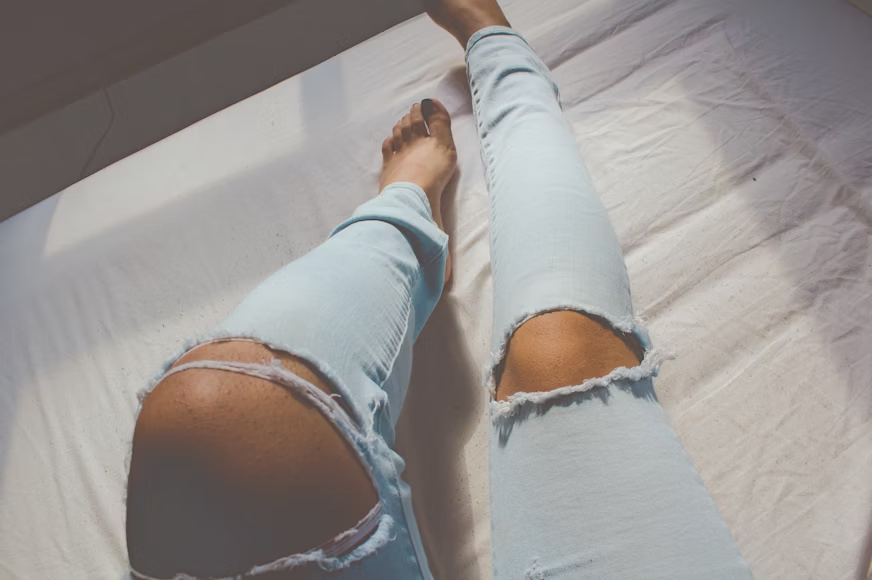 female legs wearing tight, torn denim jeans.