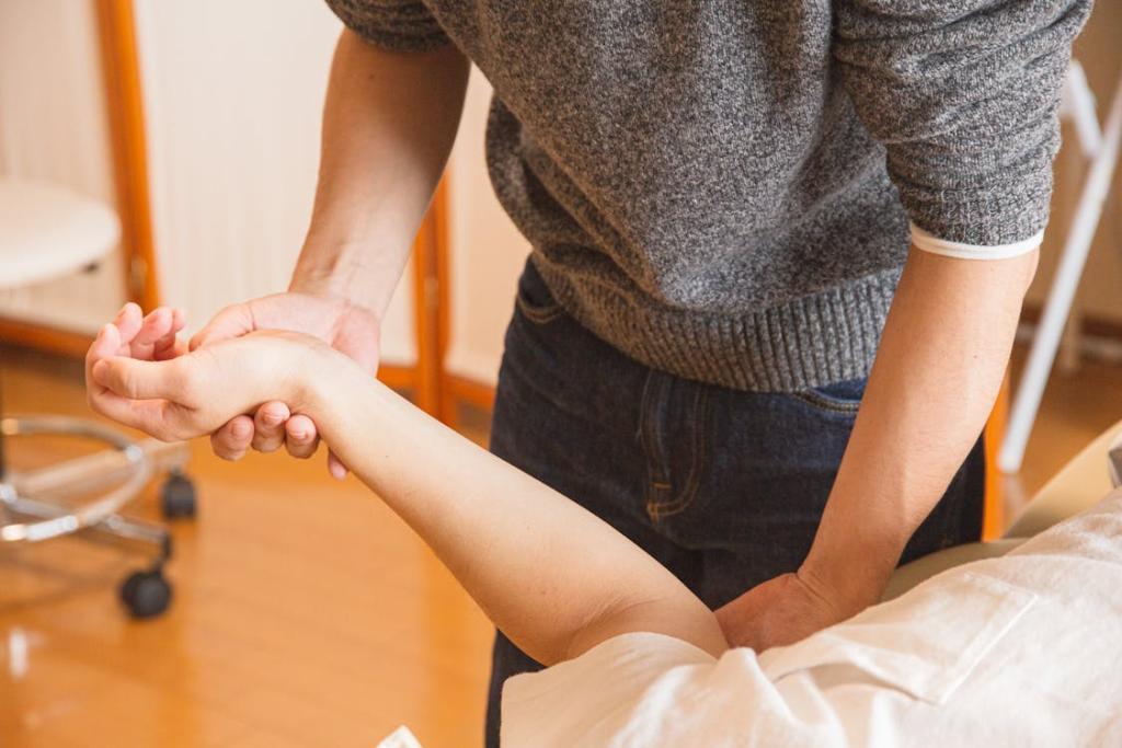 Crop chiropractor massaging hand of patient
