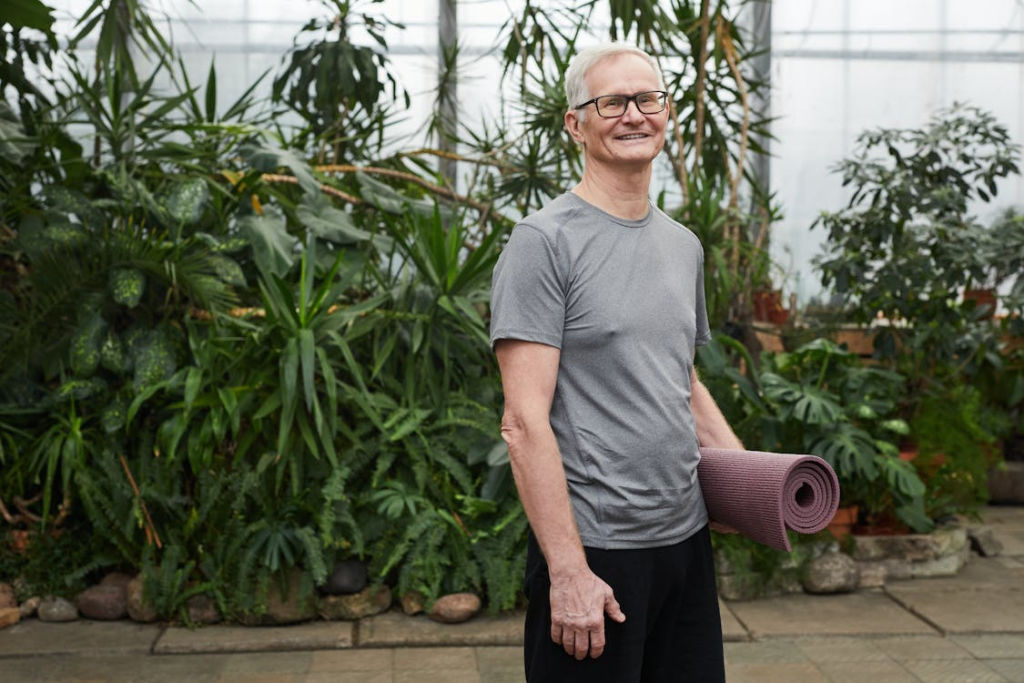 Man Standing While Holding a Yoga Mat
