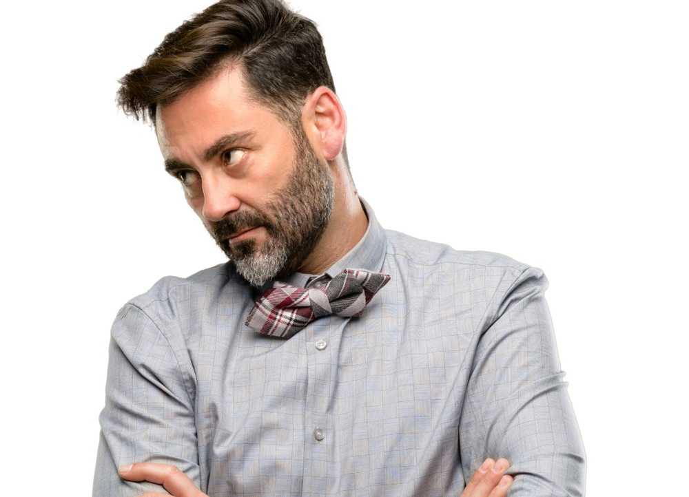 Middle age man, with beard and bow tie irritated and angry expressing negative emotion, annoyed with someone isolated over white background