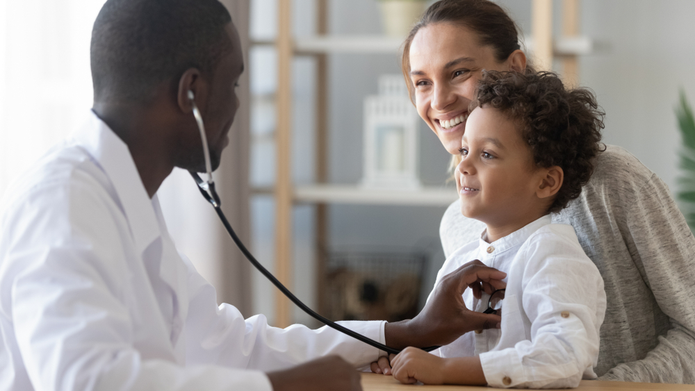 African male pediatrician hold stethoscope exam child boy patient visit doctor with mother, black paediatrician check heart lungs of kid do pediatric checkup in hospital children medical care concept
