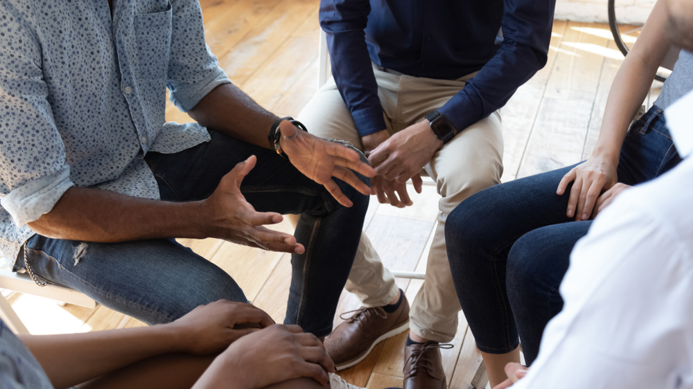 African man counselor therapist coach psychologist speak at group counseling therapy session concept encourage support patients in addiction talk share problem sit in circle in rehab, close up view
