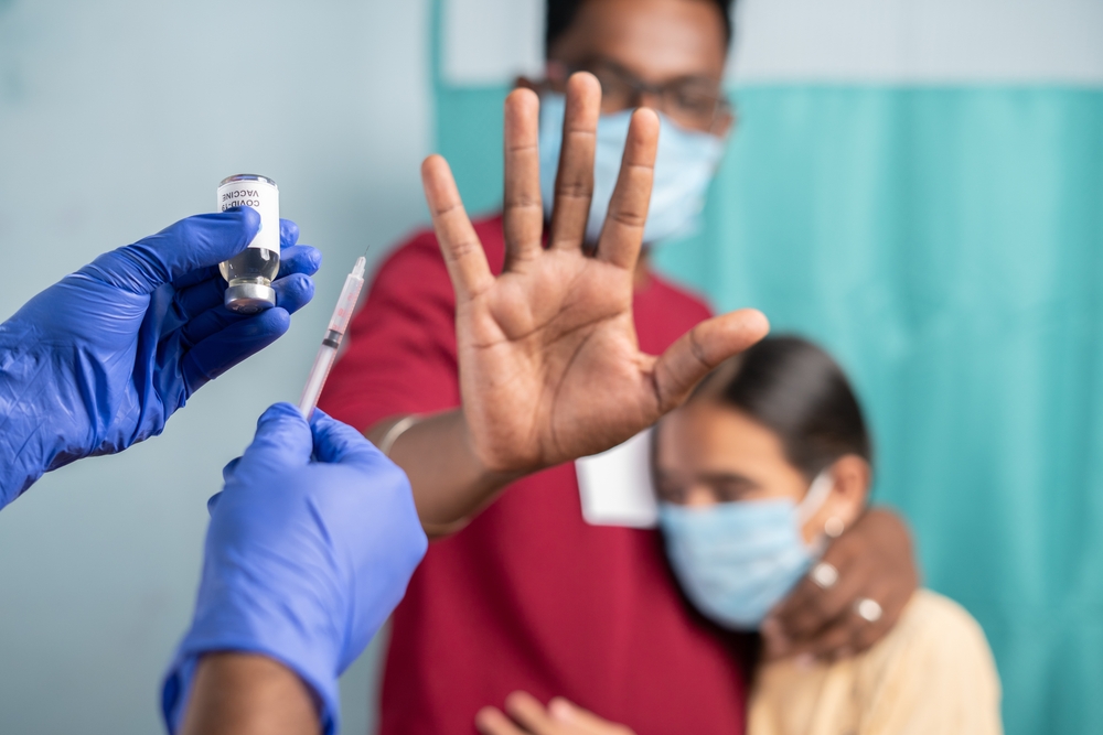 Selective focus on coronavirus vaccination bottle - Concept of Parents vaccine hesitancy for children, showing by saying no or stop gesture to vaccine with hand at hospital
