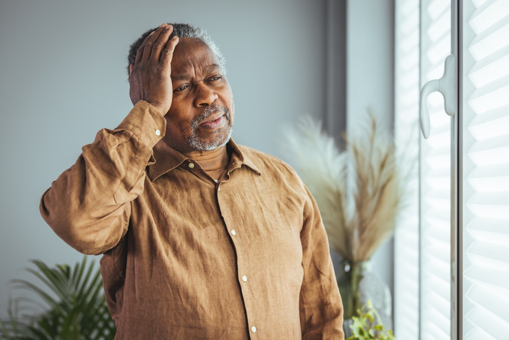 Close-up of the face of an older man from the 70's who massages his temples and holds his head, closed eyes reduces intense occasional throbbing headaches, chronic terrible migraines