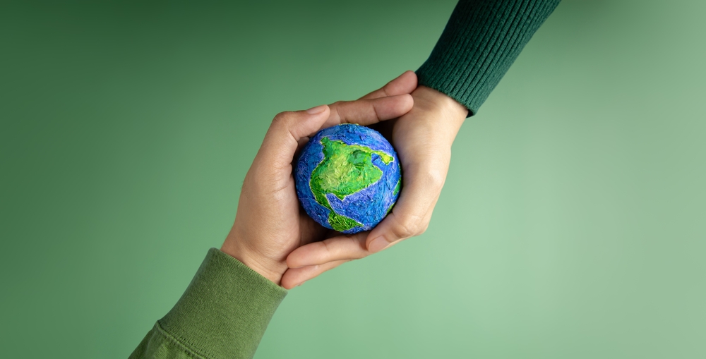 World Earth Day Concept. Green Energy, ESG, Renewable and Sustainable Resources. Environmental Care. Hands of People Embracing a Handmade Globe. Protecting Planet Together. Top View
