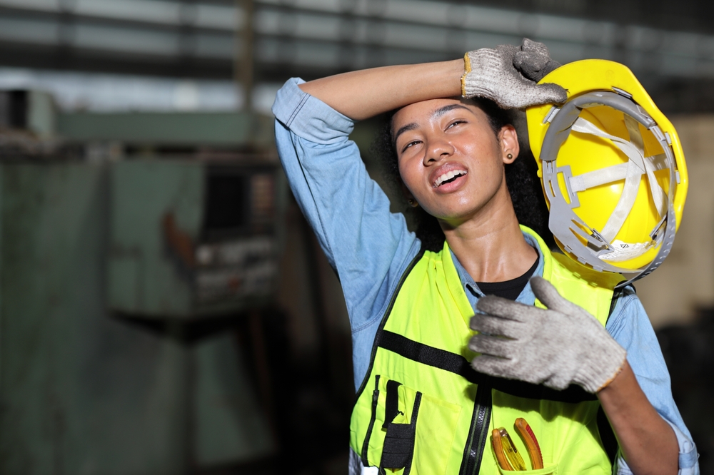 Tired technician engineer worker in protective uniform standing and taking a break while wipe the sweat away after controlling operation checking industry machine process at industry manufacturing 