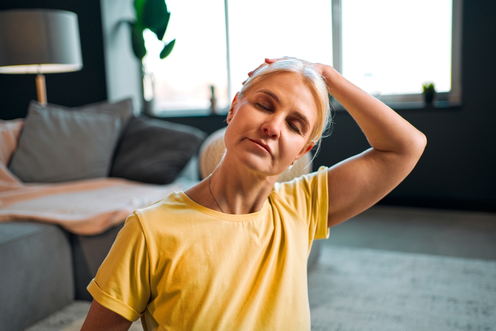 Portrait of a senior woman doing neck exercises. Sports at home.
