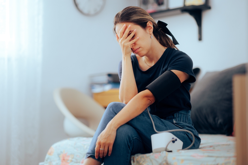Woman Taking her Blood Pressure feeling nauseated and ill. Person using a sphygmomanometer at home for health monitoring

