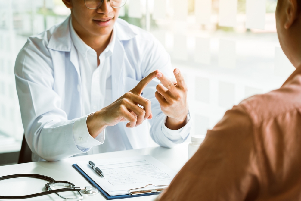 Asian doctor is examining the abnormal items of the body and diagnosing the disease in the paper with the medical report of the patient.