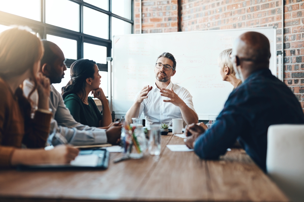 Man, manager and meeting or presentation in boardroom with coworkers for corporate business seminar. Discussion, financial and training for company growth with teamwork, leader and workshop mentor
