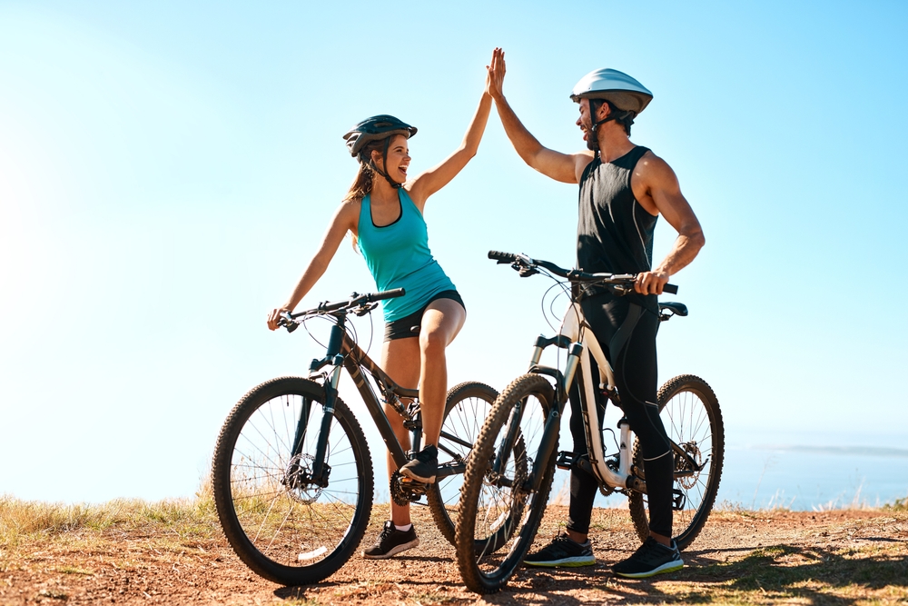 Fitness, couple and high five in mountain bike by nature for celebration, achievement and training goal. Happy people, man and woman with bicycle for exercise, workout and sports success in Germany