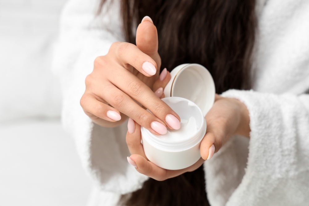 Woman in bathrobe with jar of natural cream, closeup
