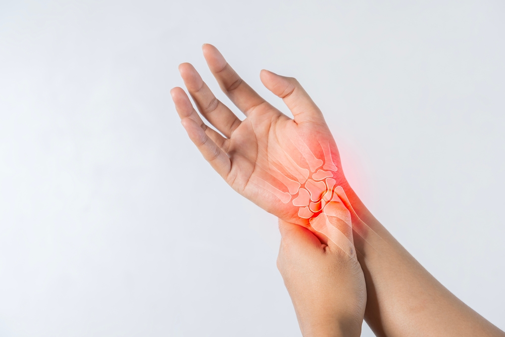 Closeup of male arms holding his painful wrist caused by prolonged work on the computer, laptop. Carpal tunnel syndrome, arthritis, neurological disease concept. Numbness of the hand