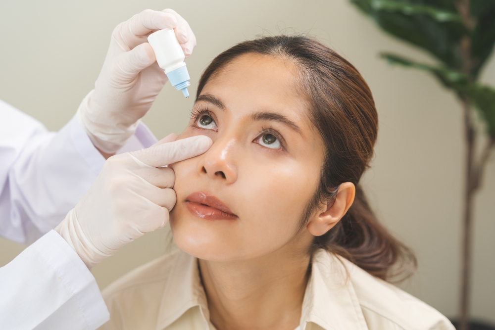 Health care concept, eye doctor eye drops to asian young woman patient, hand using medical eye drop to treat dry eye, suffering irritation or inflammation, allergy optical symptom at optic clinic.
