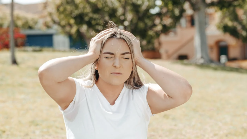 A Woman Holding her Head While Eyes Closed
