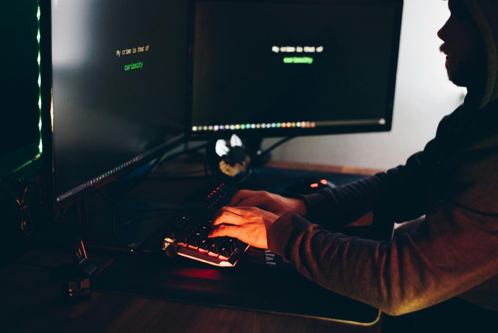 Crop hacker silhouette typing on computer keyboard while hacking system
