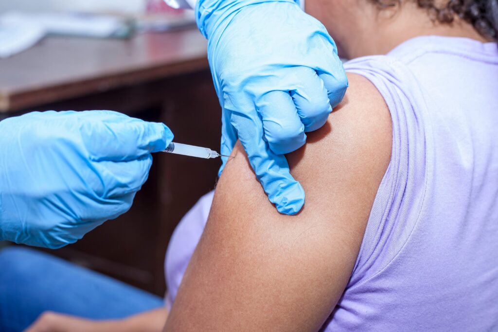A Person in Latex Gloves Injecting the Arm of a Person Wearing Lavender Shirt

