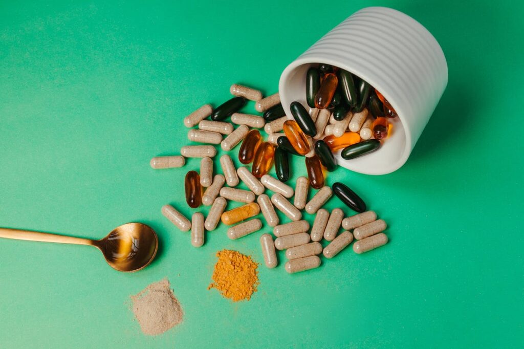Multi Colored Capsules, Bowl and Spoon on Green Surface
