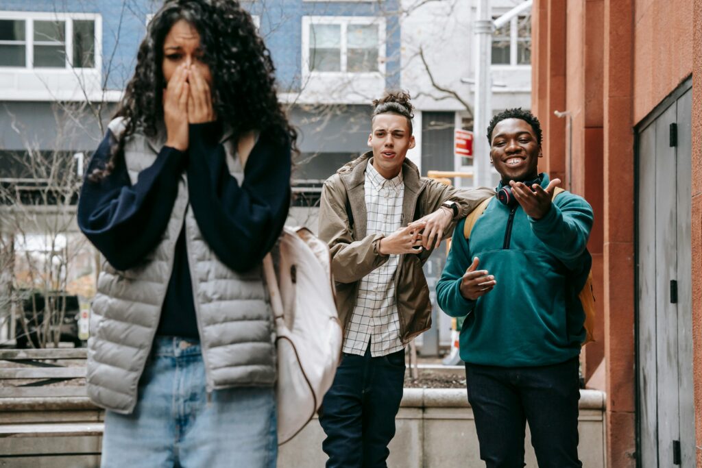 Young diverse men harassing female on street
