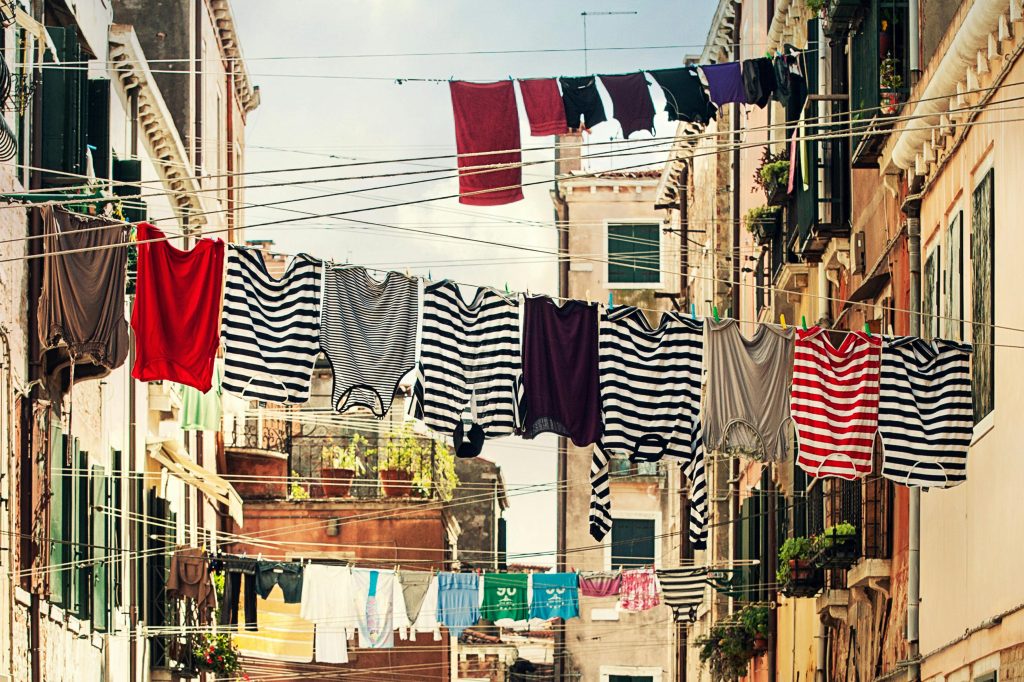 Striped Shirt Hanging on Gray Wire Between Beige Painted Wall Building during Daytime

