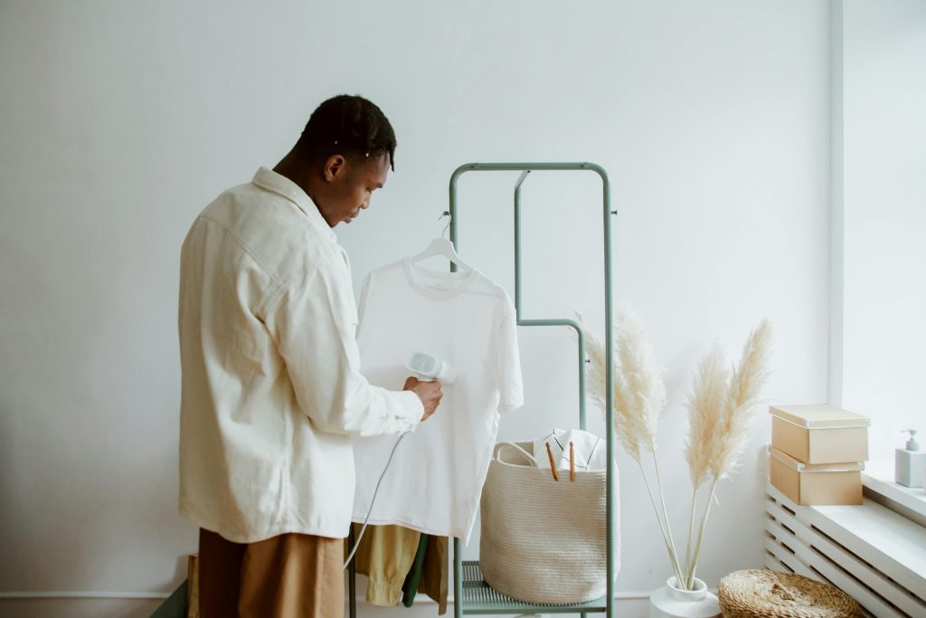 Man Steaming T-shirt on Clothing Rack
