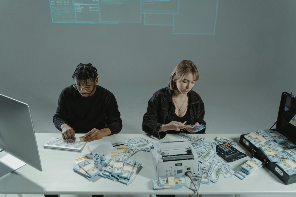 Man and woman counting large sums of money by a computer