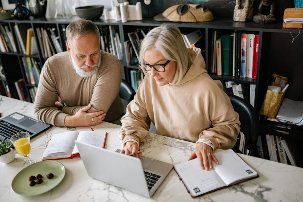 two middle aged people at laptops