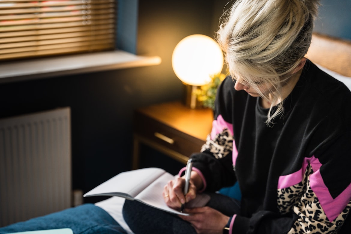 Woman journaling at desk with warm lighting, symbolizing personal health tracking and prevention planning.