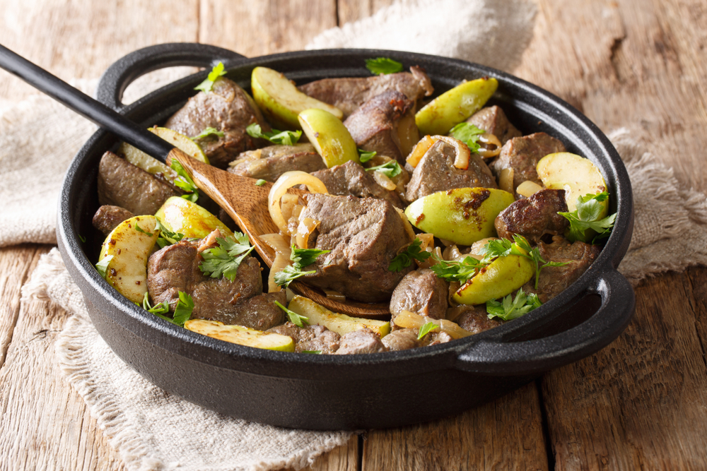 Berlin roasted beef liver with green apples, onions and herbs close-up in a pan on the table. horizontal, rustic style
