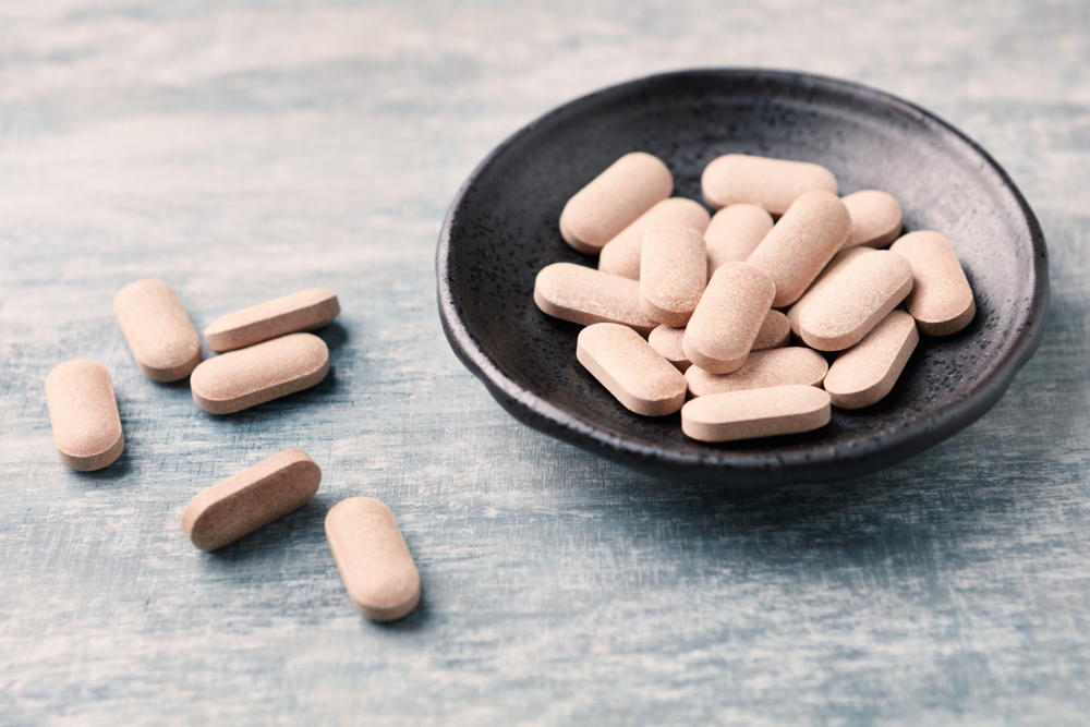 Rhodiola rosea. Golden root, rose root. Herbal pills with healthy medical plant. Healthy supplement on wooden background. Close up. 