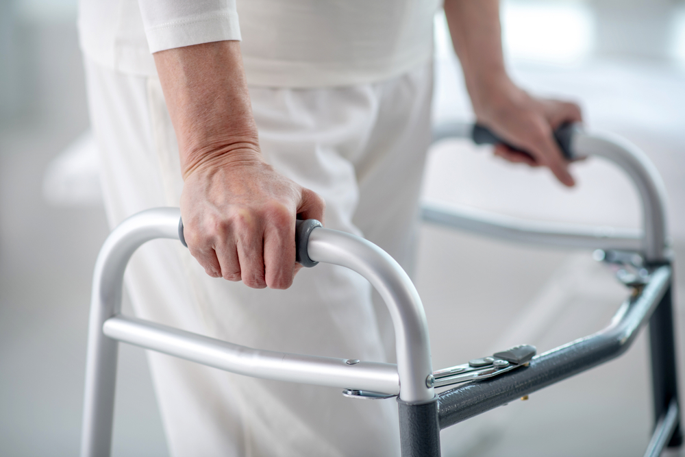 Walking disability. Close up of a female hand holding on to the walker while trying to walk
