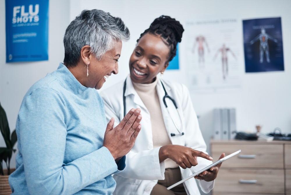 Black woman, doctor and elderly patient with good news, tablet and results for health, advice and report. Happy african medic, mobile touchscreen or healthcare with smile, tech or support in hospital

