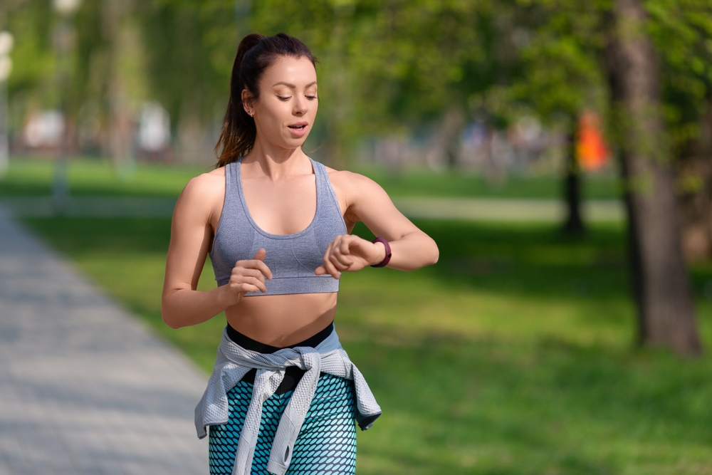Woman checks her pulse after jogging workout in the park. The concept of a healthy lifestyle and keeping fit in a fit shape.
