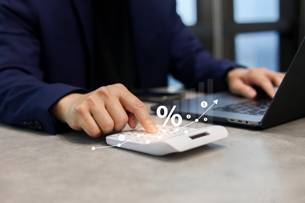 close up employee man hand use calculator for counting about expenses monthly or spending money with virtual icon of increasing inflation and interest rate for financial and economy lifestyle concept