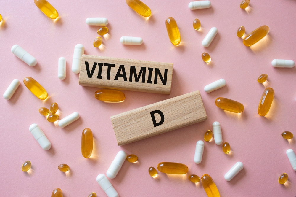 Vitamin D symbol. Concept word Vitamin D on wooden blocks. Beautiful pink background with pills. Medicine and Vitamin D concept. Copy space