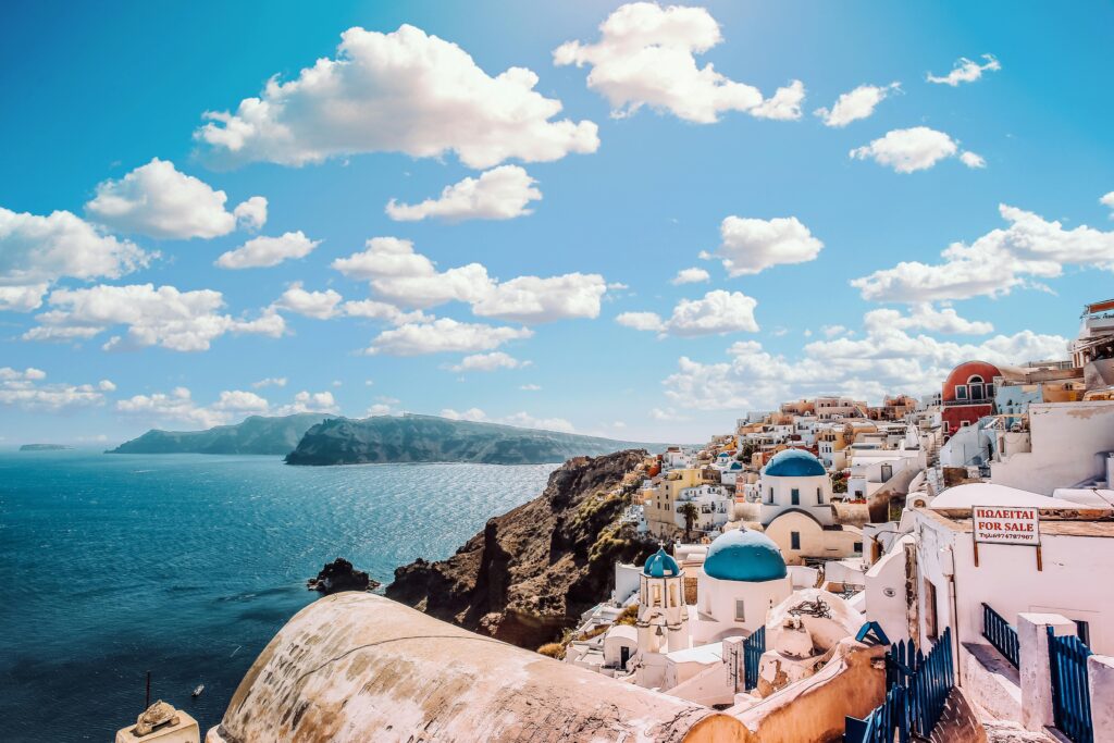 White Concrete House Near Body of Water Under White and Blue Cloudy Sky
