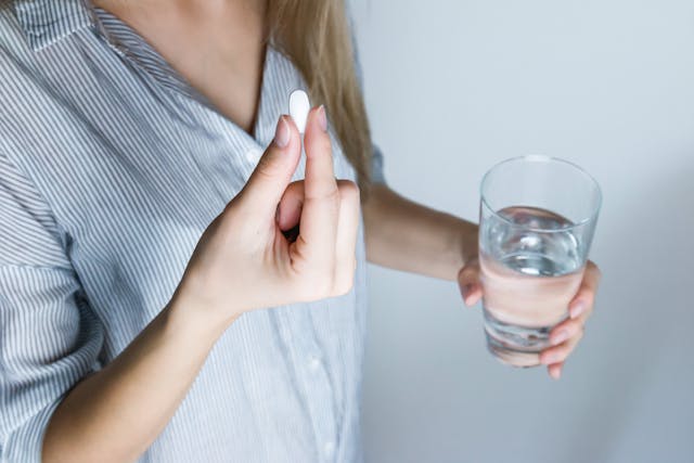 woman holding a supplement and glass of water