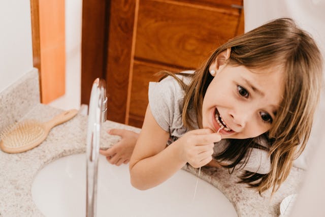 little girl flossing her teeth