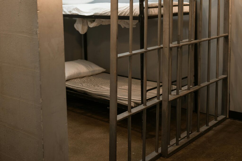 A Bunk Bed With Striped Linen Behind Bars
