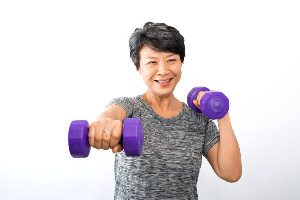 An older active senior Asian woman training, exercising, workout at home with lifting weight dumbbells isolated on white background. Exercise Active and healthy for older, elder, and senior concept.
