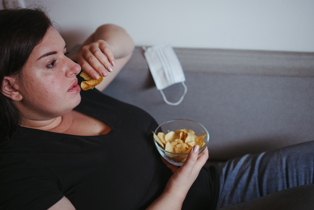 Overeating, sedentary lifestyle, bad habits, food addiction, eating disorders. Fat overweight woman lay on the coach with junk food. New normal, social distance, quarantine lockdown concept
