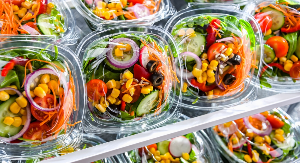 Plastic boxes with pre-packaged vegetable salads, put up for sale in a commercial refrigerator