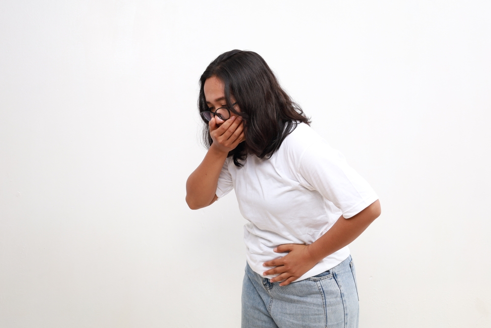 Asian Woman suffering from stomach ache and nausea on white background. Food poisoning